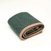 A folded dark green textured blanket with a contrasting dusty pink ribbed border, shown on a clean white background.