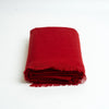 A folded red cashmere scarf with fringed edges, photographed on a clean white background.