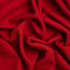A close-up of draped red cashmere fabric with soft folds and visible texture.