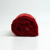 A rolled piece of deep red cashmere fringed fabric, shown on a clean white background.