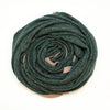 A dark forest green textured knit blanket, rolled into a spiral shape, displayed on a clean white background.