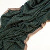 Evergreen Heather cashmere travel blanket draped over sofa