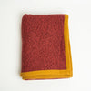Terracotta Heather cashmere throw blanket with Golden Ochre trim, folded
